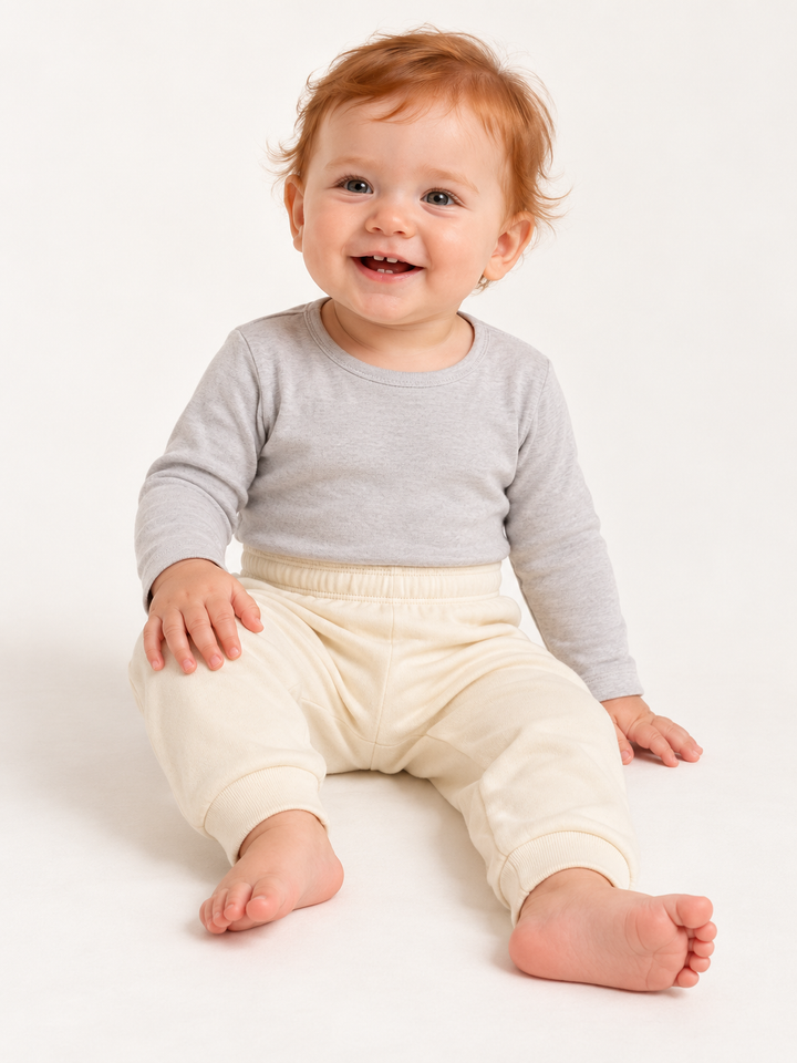 Sitztgut Baby-Jogginghose in Natur am fiktiven Baby-Modell, elastischer Bund und Rippbündchen sichtbar
